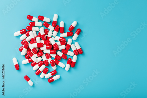 A handful of Red and white pill capsules on a blue background. Free space Top view