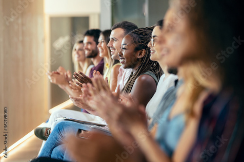 Happy business team clapping after listening the conference while sitting on coworking space.