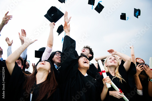 Group of diverse grads throwing caps up in the sky
