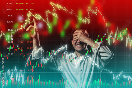 Scared trader pointing to volatile stock market charts with eyes closed.