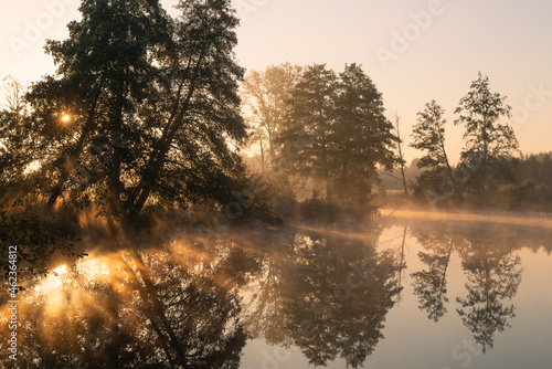 Jesienny pejzaż nad wodą. Mgły, drzewa, promienie słońca, rzeka. Staw w Białej na rzece Czerniawce, Gmina Zgierz