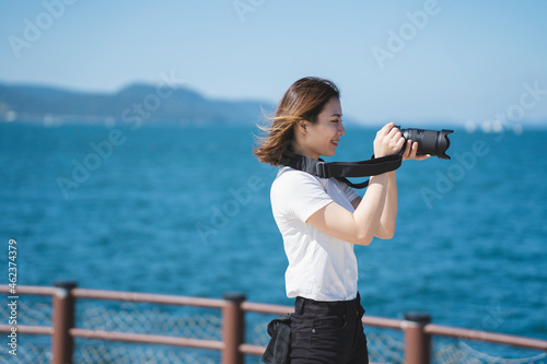 海辺で写真を撮るカメラ女子