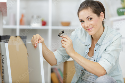 young woman assembling furniture in new apartment
