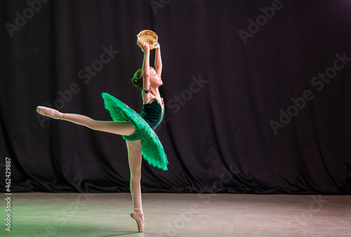 A little girl ballerina is dancing on stage in a tutu on pointe shoes with a tambourine, a classic variation of Esmeralda.