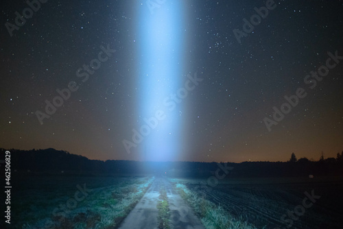 Smuga światła nad polną drogą, na tle nocnego, gwieździstego nieba.