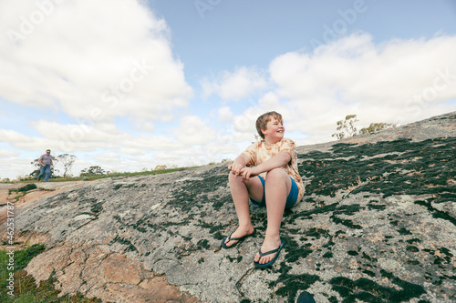 Happy caucasian boy sitting on large rock in National Park