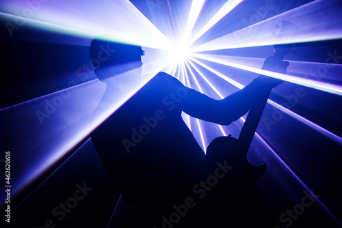 Mężczyzna z gitarą na tle światła laserowego