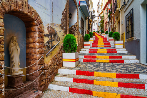 Narrow alley decorated with the flag of Spain on the steps. Calpe Alicante.