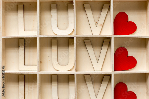 the word love (luv) in wooden letters arranged in a shallow box with square compartments