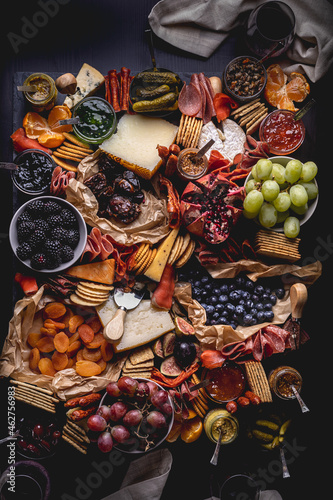 Charcuterie with fruit, meat, cheese, crackers, olives, pickles, jam, mustard