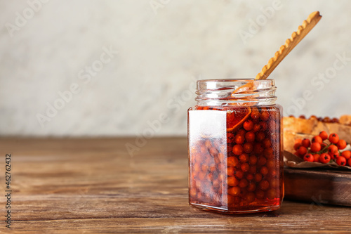 Jar of delicious rowan jam on wooden table