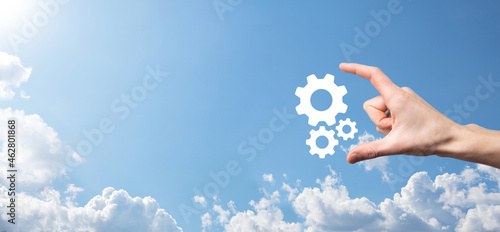 Male hand holding cog gears icon ,mechanism icon on virtual screens on blue background. Automation Software Technology Process System Business concept. Banner