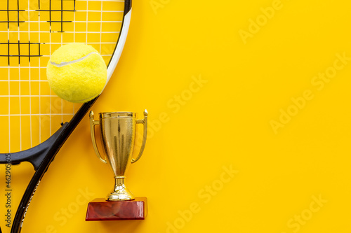 Small golden trophy cup with tennis racket and ball. Sport champion winner concept