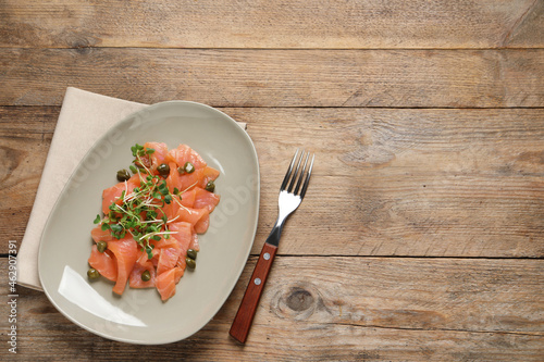 Delicious salmon carpaccio served on wooden table, flat lay. Space for text