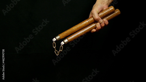 Man's hand holding a nunchaku in his hand. White weapon concept.
