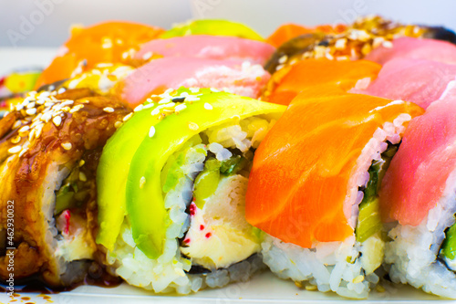 Tasty Colorful assorted Set of different type Sushi. Dinner in Japanese style. Healthy food. Filadelfia and Maki sushi rolls with Avocado, Tuna, Salmon, fish and Prawns. Close up view. Wallpaper.