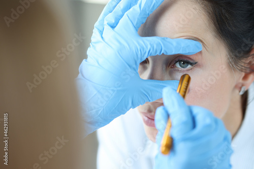 Doctor shines light into patient eye to check pupil closeup