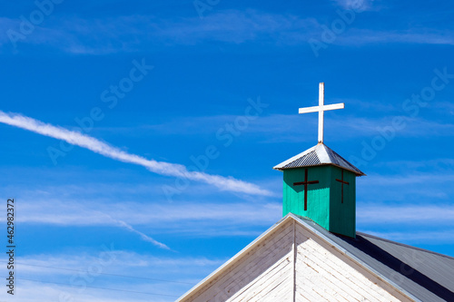 Green steeple with white cross on the steeple of an old church in New Mexico’s Manzano Mountains