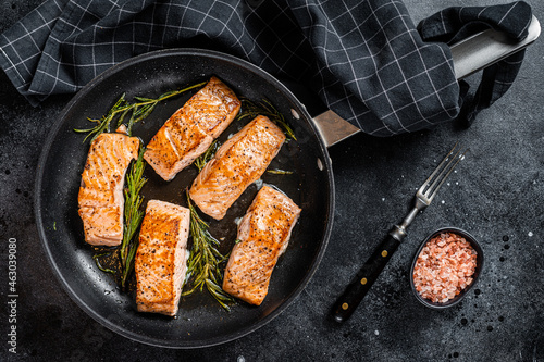 Roasted Salmon Fillet Steak in a pan with rosemary. Black background. Top view
