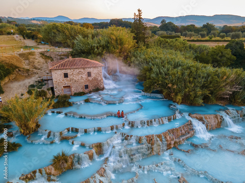 natural spa with waterfalls and hot springs at Saturnia thermal baths, Grosseto, Tuscany, Italy,Hot springs Cascate del Mulino man and woman in hot spring taking a dip during morning with fog