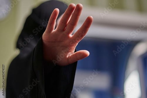 A Muslim woman in traditional black clothing nikab showing stop hand gesture. Role of women in Islamic world. Domestic violence, discrimination of Muslim women. Stop domestic violence against women