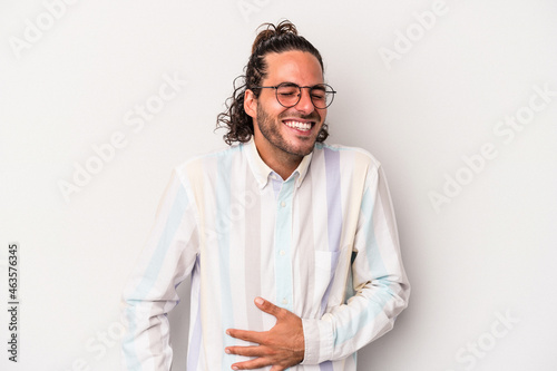 Young caucasian man isolated on gray background touches tummy, smiles gently, eating and satisfaction concept.