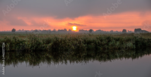Panorama of sunset over fields of polder and Kromme Ie canal in Friesland, Netherlands