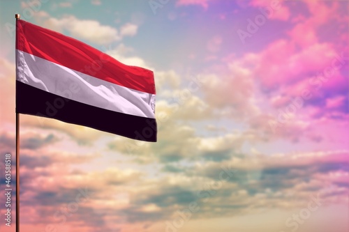 Fluttering Yemen flag mockup with the space for your content on colorful cloudy sky background.