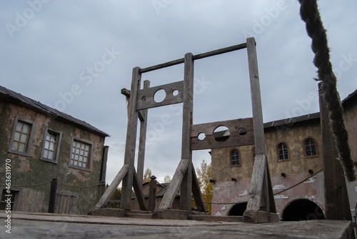 Scaffold with two blocks for criminals against the background of houses of an abandoned medieval city. Medieval execution weapon