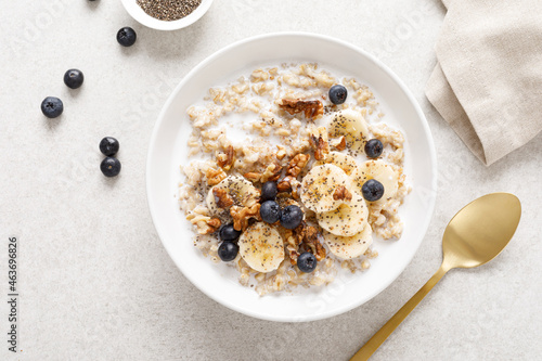 Oatmeal bowl. Oat porridge with banana, blueberry, walnut, chia seeds and almond milk for healthy breakfast or lunch. Healthy food, diet. Top view.