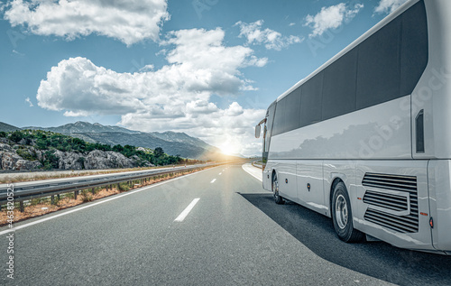 White passenger bus on the highway against the backdrop of a beautiful landscape.