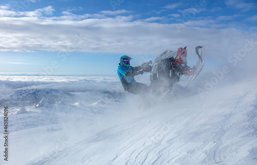 a cool snowmobiler goes to the top of the mountain at high speed with snow eddies, holding the snowmobile on the "heel". the concept of extreme recreation