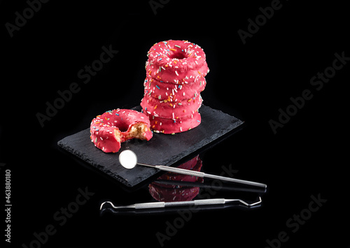 torre de donuts encima de un plato de pizarra sobre fondo negro e instrumental de dentista
