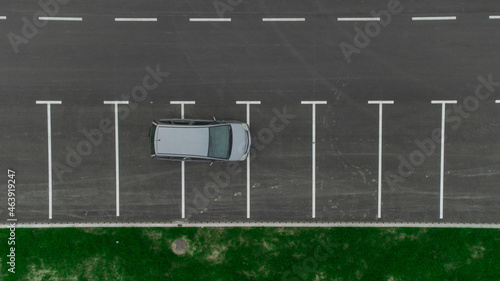 Stupid driver parking. A car parked over multiple parking spots. Car perpendicular to parking spots viewed from above. Aerial drone view of bad parking habit.