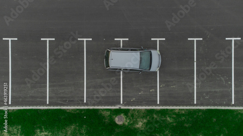 Stupid driver parking. A car parked over multiple parking spots. Car perpendicular to parking spots viewed from above. Aerial drone view of bad parking habit.