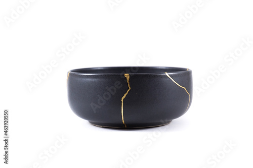 Isolated Japanese kintsugi black bowl restored with real gold , black pottery with gold cracks