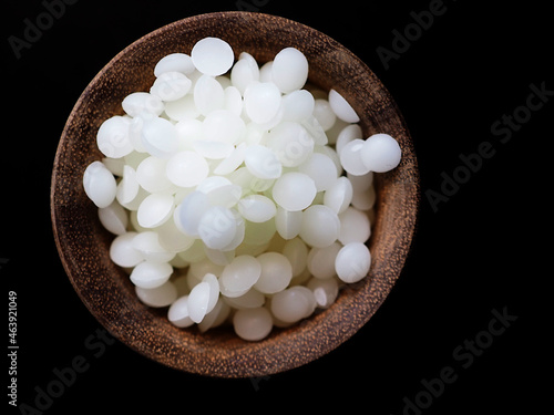 White refined cosmetic beeswax pearls on black background