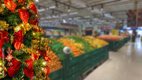 Christmas tree detail with supermarket fruit sector blurred background. selective focus.