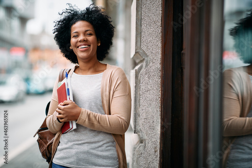 Happy African American mid adult student in front of the library.