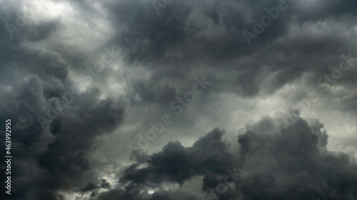 gray stormy dramatic sky with overcast and heavy textured cumulus clouds and backlight. large panoramic view