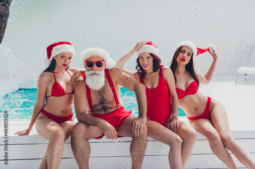 Photo of suspicious funny santa claus snow maidens wear bikinis enjoying pool water looking you celebrating noel outdoors villa spa hotel