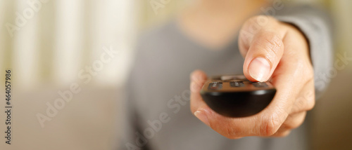 Woman presses online TV remote at home