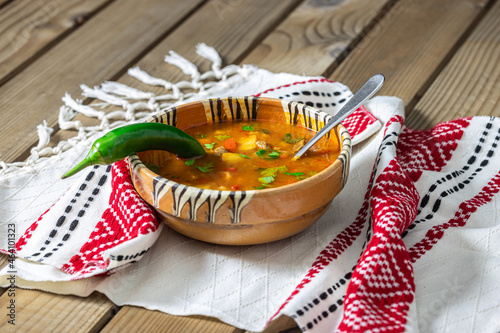 Romanian traditional beef soup served in clay bowl on traditional towel. In romanian is called "ciorba de vacuta".