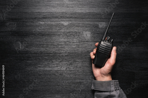 A worker with a walkie talkie radio station in the hand on the black flat lay background with copy space.