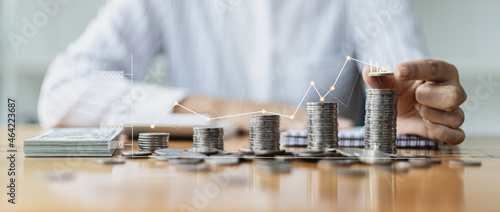 Business Woman putting a coin on a pile of coins. Placing coins in a row from low to high is comparable to saving money to grow more. The concept of growing savings and saving by investing in stock