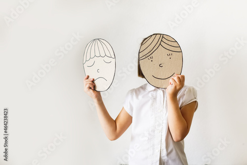 child with masks of emotions, joy and sadness. Psychology and children's emotions concept