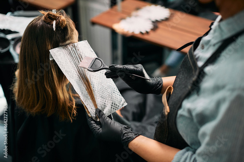 Close-up of hairdresser dyes customer's hair at the salon.