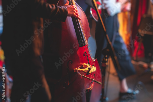 Concert view of a contrabass violoncello player with vocalist and musical band during jazz orchestra band performing music, violoncellist cello jazz player on the stage