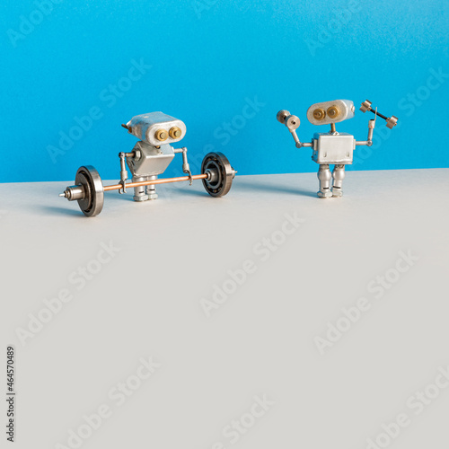 Robot weightlifter and robotics athlete train with heavy barbell and light fitness dumbbells. Power sport, fitness weightlifting workout. blue gray background, copy space.