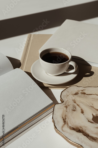 Home office workspace with blank paper sheet notebook, coffee cup, marble tray in sunlight shadows. Aesthetic luxury bohemian minimal lady boss business lifestyle concept